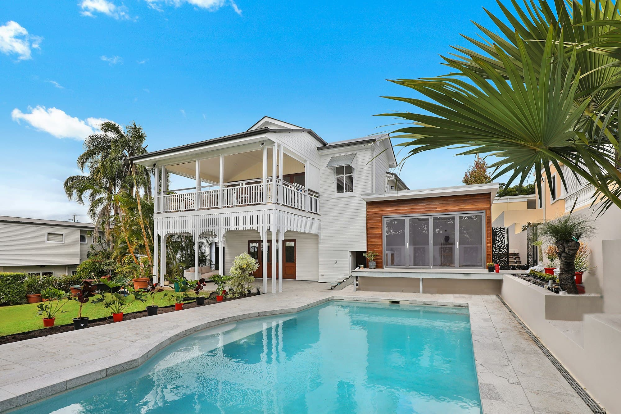 Backyard pool beside a house framed by palms
